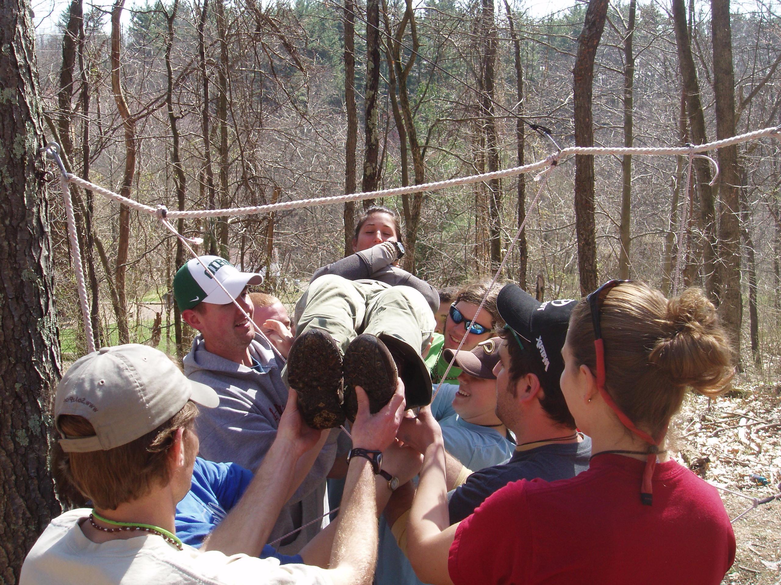 Group of people lifting a woman through a rope spider web