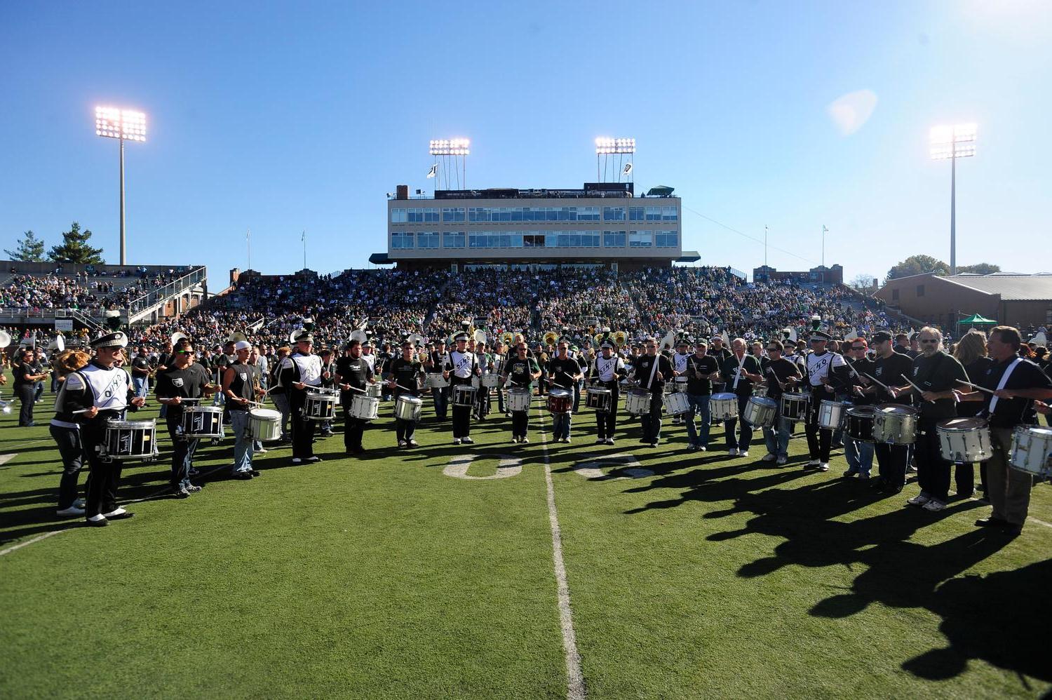 Marching 110 alumni play their instruments on the field